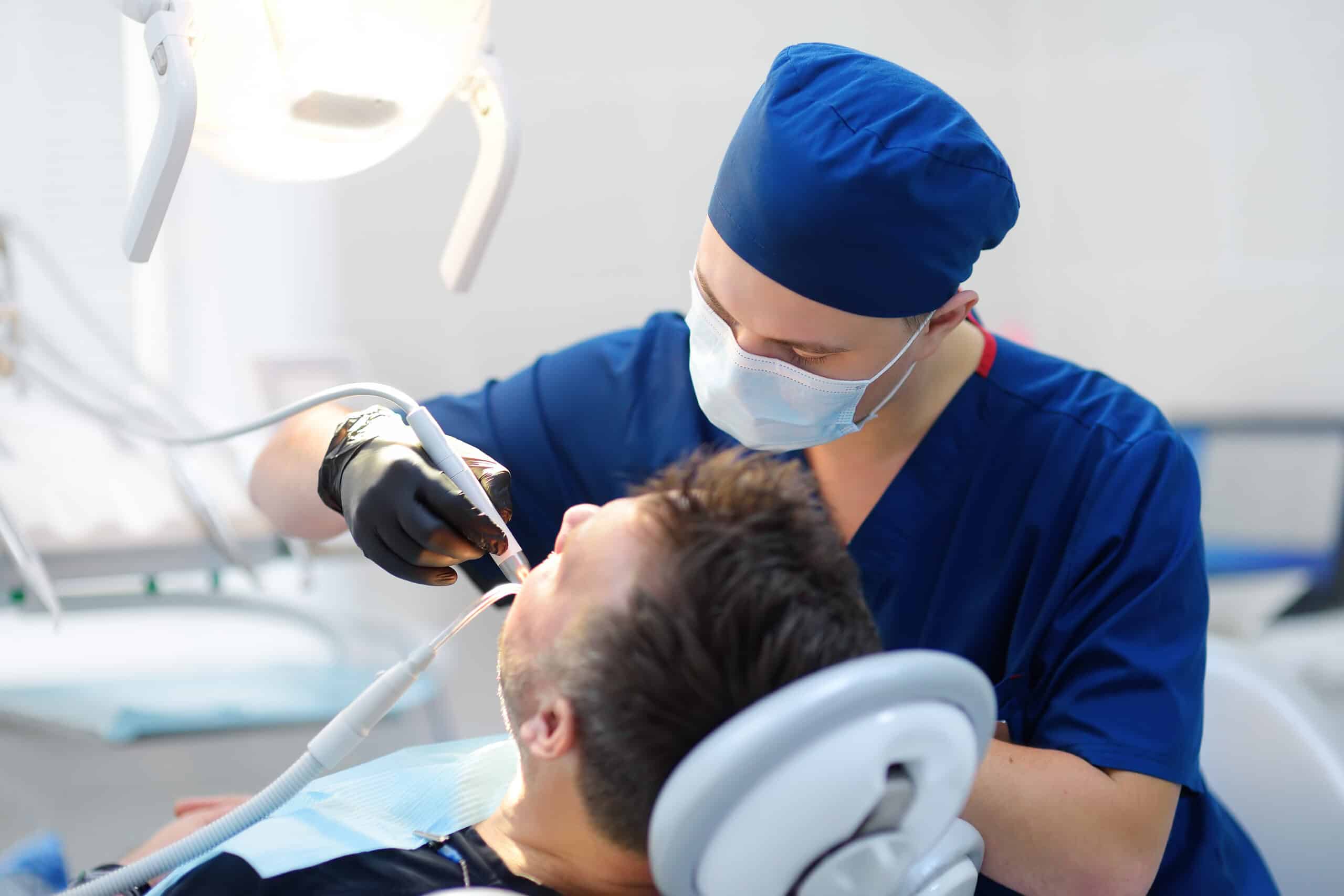 Dentist and patient at medical center. Doctor treats a mature man teeth with dental drill. Orthodontist and prosthetics appointment. Hygiene and teeth healthy.
