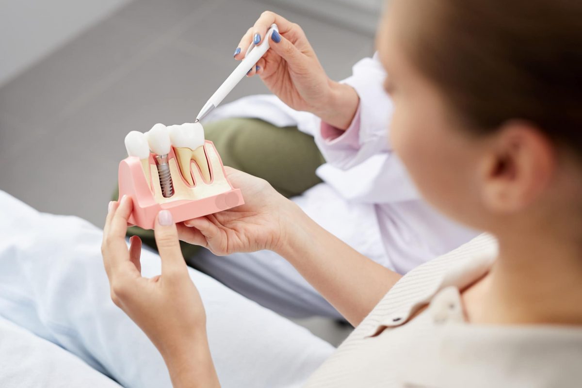 High angle view of unrecognizable young woman holding tooth model during consultation in dentists office, copy space